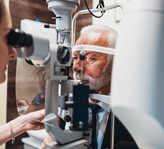 Elegant senior bearded man receiving ophthalmology treatment. Doctor ophthalmologist checking his eyesight with modern equipment.